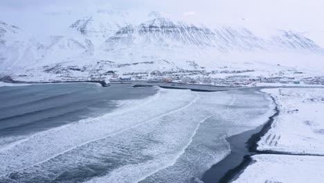Aerial-View-Of-Olafsfjordur-Fishing-Town-In-North-Iceland,-Revealing-Fish-Racks-On-The-Snowy-Shore-In-Early-Winter