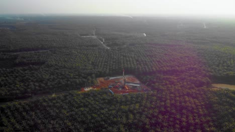 Cinematic-4K-Drone-Footage-of-Onshore-Drilling-Rig-equipment-structure-for-oil-exploration-and-exploitation-in-the-middle-of-jungle-surrounded-by-palm-oil-trees-during-sunset-and-high-oil-price