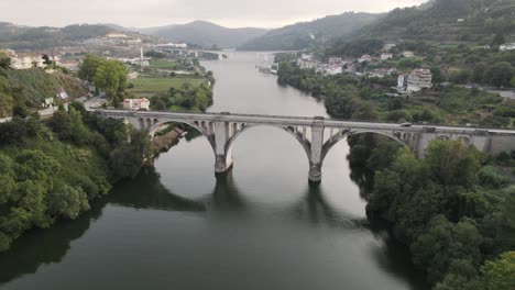 Aéreo-Descendiendo-Lentamente,-Hermoso-Puente-Arqueado-Entre-os-rios-Río-Tâmega,-Portugal