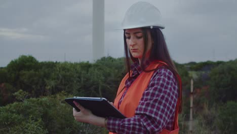 Medium-closeup-of-female-windmill-technician-uses-tablet-to-inspect-wind-turbine