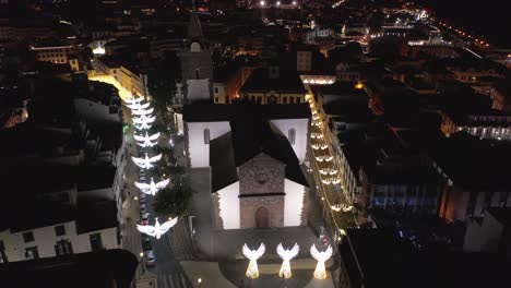Cathedral-of-Funchal-with-white-glowing-angel-decoration-during-Christmas,-aerial