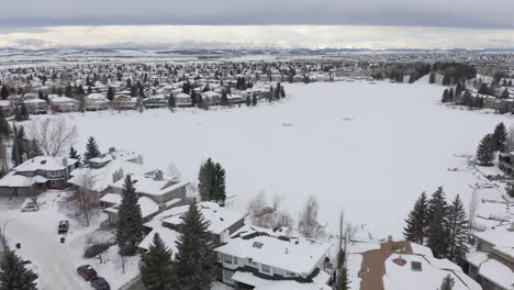 Casas-Alrededor-De-Un-Lago-Congelado-En-Las-Praderas-De-Alberta,-Canadá-Congeladas-Por-Un-Dron