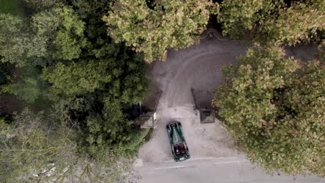 Classic-green-colored-convertible-car-entering-a-villa-gate-in-the-south-of-France,-Aerial-looking-down-shot