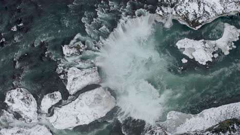 Magnificent-birds-eye-view-of-Godafoss-waterfall-in-north-Iceland-snow-during-winter-conditions---aerial-straight-top-down
