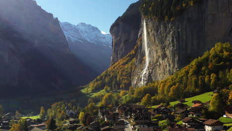 Rotating-drone-shot-of-a-village-and-Staubbach-waterfall-in-Lauterbrunnen,-Switzerland
