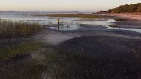 Photographer-on-sandy-lagoon-shore-at-dusk,-Laguna-Negra-in-Uruguay
