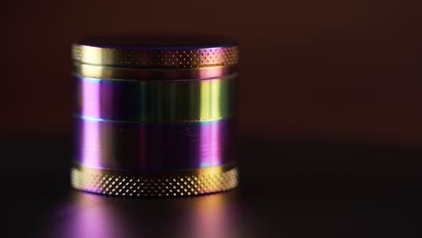 A-multicolored-cannabis-grinder-slowly-turning-left-with-colourful-reflections