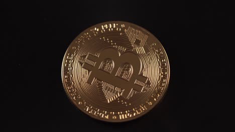 Goldenes-Bitcoin-Asset,-Das-Sich-Mit-Schwarzem-Hintergrund-Dreht,-Makro-Von-Oben-Nach-Unten