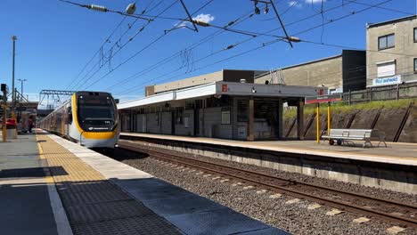 Train-arriving-at-platform-3-of-Bowen-Hills-station,-inner-city-travel-on-a-sunny-day,-Translink-Queensland-railway-public-transportation,-Brisbane-city,-Australia