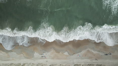 Aerial-top-down-shot-over-breaking-waves-Wrightsville-Beach,-North-Carolina-TRACKING-LEFT-TO-RIGHT