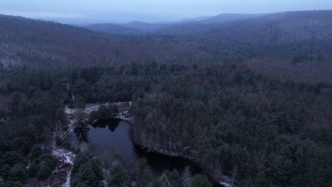 Aerial-drone-video-nightfall-time-lapse-of-a-beautiful-snowy,-foggy-evening-with-low-clouds-in-the-Appalachian-mountains-during-winter