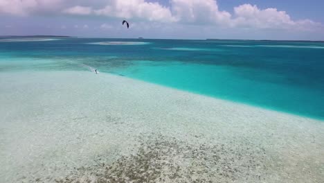 Drone-Shot-Man-Kitesurf-Alrededor-Del-Arrecife-De-Coral,-Textura-De-Agua-De-Mar,-Archipiélago-De-Los-Roques