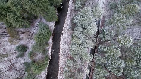 Aerial-drone-video-footage-of-a-snowy-pine-forest,-stream,-and-a-quiet-country-road-in-the-appalachian-mountains-during-winter