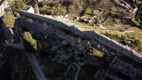 AERIAL---Ancient-city-walls-of-Kotor,-Montenegro,-forward-tilt-down-to-top-down