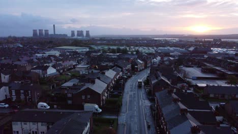 Rainy-industrial-townhouse-rooftops-at-sunrise-with-power-station-on-horizon-aerial-view