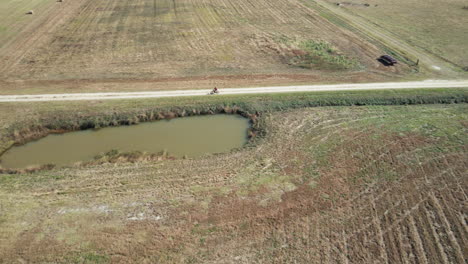 Aerial-shot-tracking-cyclist-cycling-through-fields-in-Burgaw,-North-Carolina