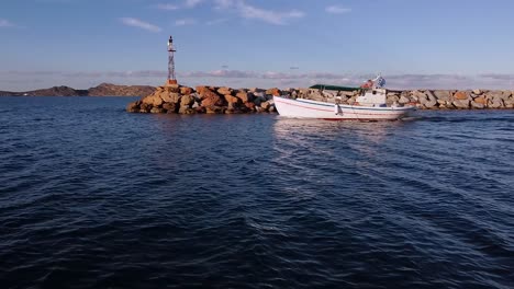 Small-boat-passes-in-front-of-lighthouse