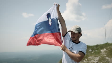 Wanderer,-Der-Eine-Slowenische-Flagge-Hochhält,-Um-Im-Wind-Zu-Flattern