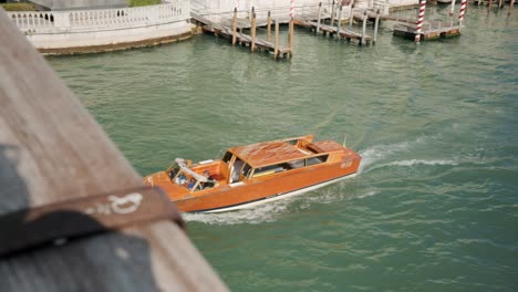 Traditional-Wooden-Water-Taxi-Boat-Traveling-Across-The-Grand-Canal-In-Venice,-Italy