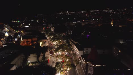 Decorative-Christmas-lights-in-trees-with-on-idyllic-street-in-Funchal,-aerial