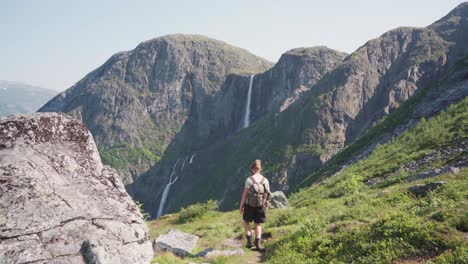 Excursionista-Masculino-Con-Mochila-Caminando-Por-Un-Sendero-Que-Conduce-A-La-Cascada-Mardalsfossen-En-El-Condado-De-More-Og-Romsdal,-Noruega