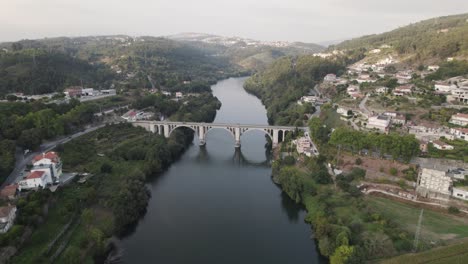 Aerial-descending-approach-of-Ponte-De-Pedra-old-historic-bridge-at-Entre-Os-Rios-in-Portugal