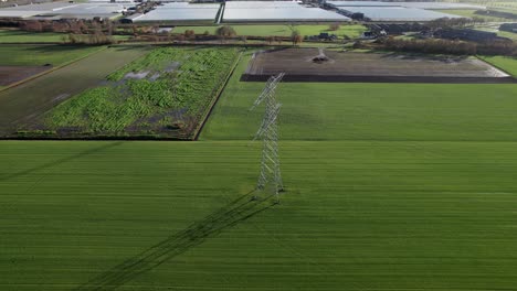 Camera-slowly-tilts-down-on-lattice-tower-standing-in-the-agricultural-landscape