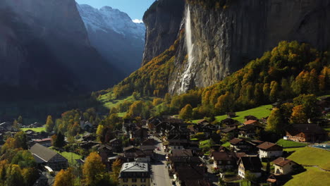 Cinematic-up-tilting-drone-shot-of-a-village-in-Lauterbrunnen,-Switzerland-with-the-Staubbach-Waterfall-in-the-background
