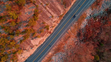Aerial-drone-top-down-video-footage-of-a-beautiful-mountain-highway-during-fall-autumn-in-the-Appalachian-Mountains,-with-golden-light-at-sunset