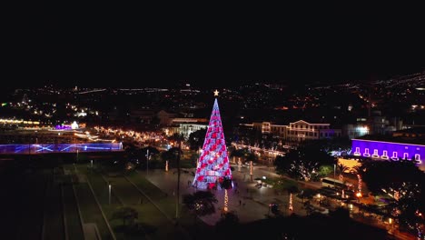 Tall-light-art-Christmas-tree-at-Praça-do-Povo-park-in-Madeira-during-holiday-season,-aerial