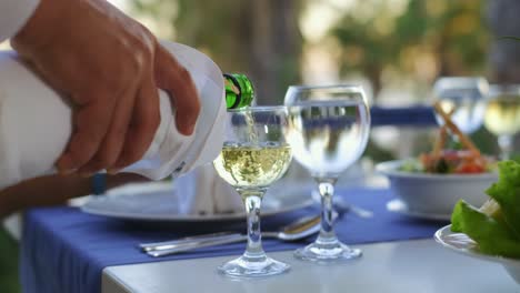 The-Waiter-pours-white-wine-in-wine-glass-In-The-Restaurant