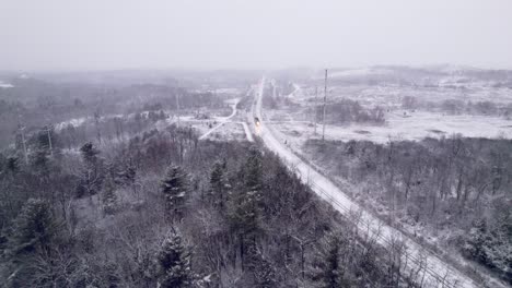 El-Tren-De-Cercanías-Se-Acerca-Durante-Una-Ventisca-En-Un-Paisaje-Invernal-Cubierto-De-Nieve,-Rastreando-Drones-Aéreos,-Ontario,-Canadá