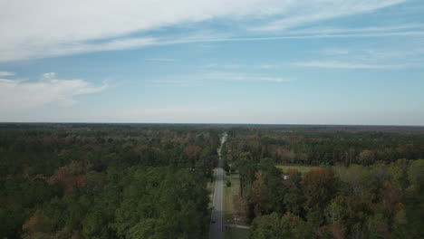 Wide-aerial-above-road-cutting-through-dense-forest-towards-horizon