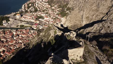 AERIAL---City-walls-and-Bay-of-Kotor,-Montenegro,-World-Heritage-Site,-top-down-tilt-up