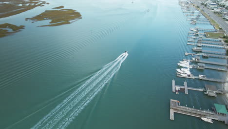 Aerial-tracking-speedboat-driving-along-Wrightsville-Beach,-North-Carolina