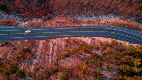 Aerial-drone-footage-panning-upward-of-the-shawangunk-mountains,-a-scenic-highway,-and-the-hudson-valley-in-new-york-state-during-autumn-at-sunset