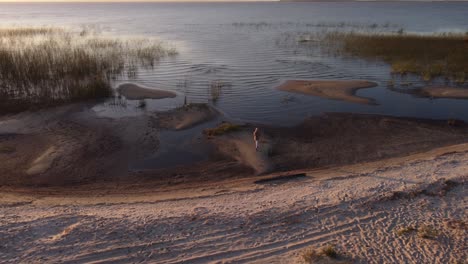 Luftaufnahme-Eines-Fotografen,-Der-Am-Sandigen-Ufer-Spazieren-Geht,-Um-Während-Des-Sonnenuntergangs-Bilder-Der-Malerischen-Seenlandschaft-Von-Uruguay-Zu-Machen