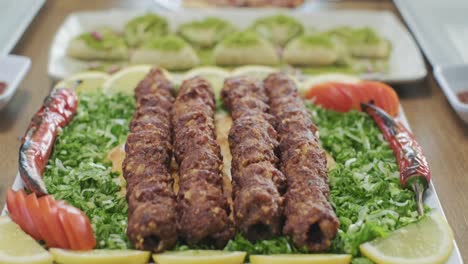 Waiter-serving-traditional-Turkish-kebab-plate-with-green-onions-and-tomatoes
