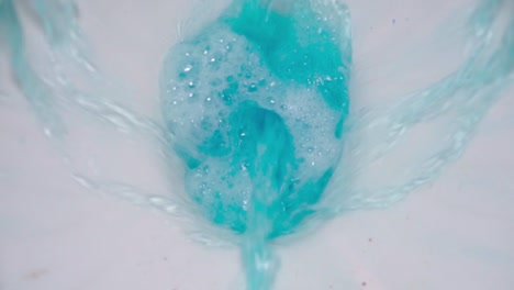 Close-up-of-flushing-toilet-with-blue-cleaning-product