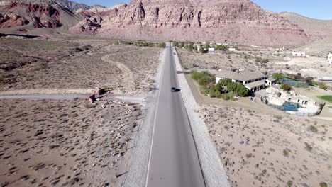 Drone-Tracking-Shot-of-Car-Driving-along-Red-Rock-Canyon-Highway,-Las-Vegas,-Nevada