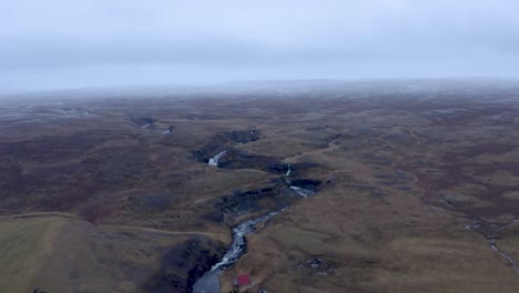 Aerial-backwards-flight-showing-icelandic-Sela-River-in-North-Iceland-during-cloudy-autumnal-day