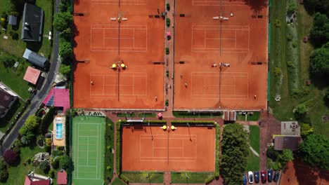 Tennis-courts-with-playing-people,-top-down-drone-aerial-view,-sunny-day