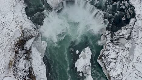 Spectacular-drone-shot-of-mighty-Godafoss-waterfall-in-North-Iceland-during-icy-winter-day--aerial-tilt-up-shot