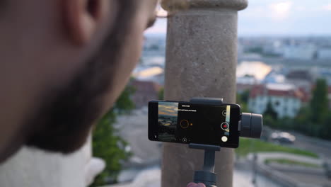 Nahaufnahme-Eines-Mannes,-Der-Mit-Smartphone-Und-Gimbal-Den-Sonnenaufgang-über-Der-Stadt-Budapest-Filmt