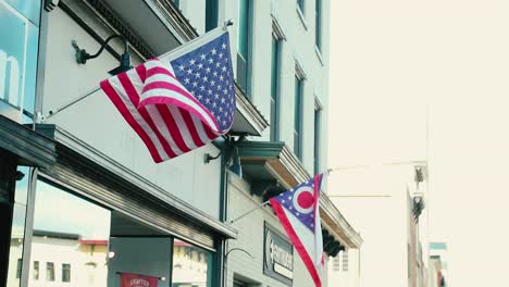 Glorious-US-and-Ohio-American-flags-wave-in-the-bresze-in-front-of-a-small-business-over-the-sidewalk-in-a-small-quaint-town
