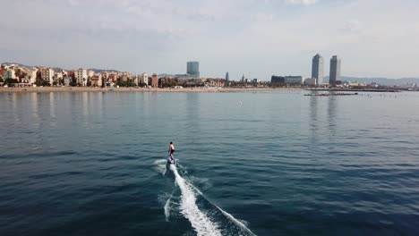Elektronisches-Surfen-Am-Strand---Surfer-Mit-Elektrischem-Brett,-Der-Entlang-Der-Küste-Von-Barcelona-In-Spanien-Reitet---Drohnenaufnahme