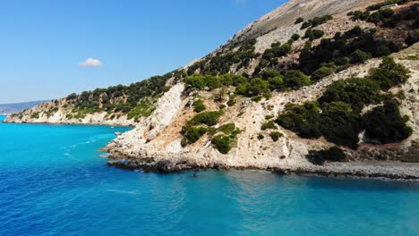 Blue-Calm-Waves-by-the-Agia-Kiriaki-Beach-and-Lush-Cliffs-in-Greece---aerial-pullback