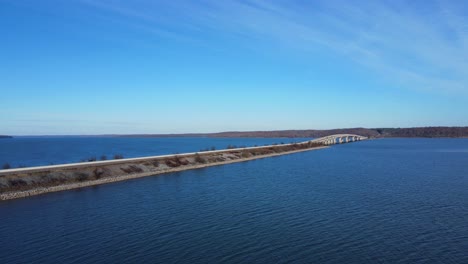 Aerial-rise-of-a-bridge-rising-over-a-blue-lake-with-blue-skies