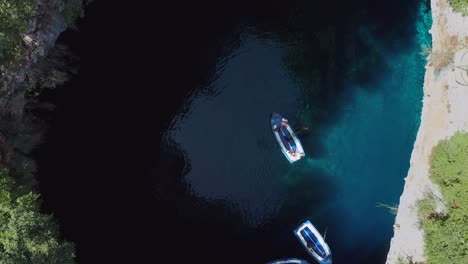 Aerial-top-down-view-boat-tour-on-Melissani-cave,-crystal-clear-water,-Greece