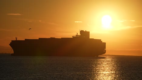 Silhouette-Eines-Riesigen-Containerfrachtschiffs,-Das-Während-Einer-Globalen-Lieferkettenkrise-Während-Eines-Goldenen-Sonnenuntergangs-Im-Hafen-Angedockt-Ist